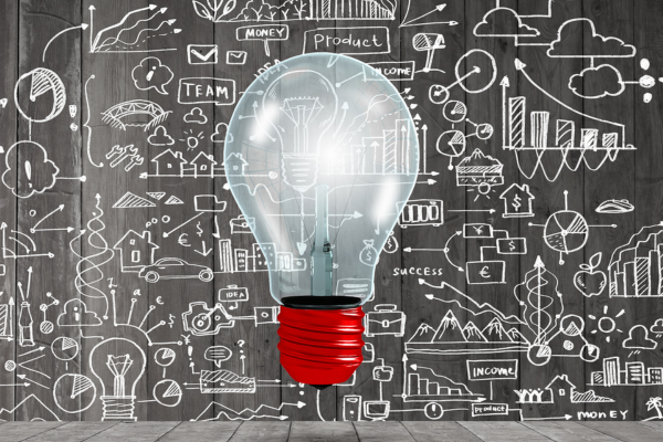 Lightbulb overlaying a chalkboard background with various symbols and images representing business and personal life
